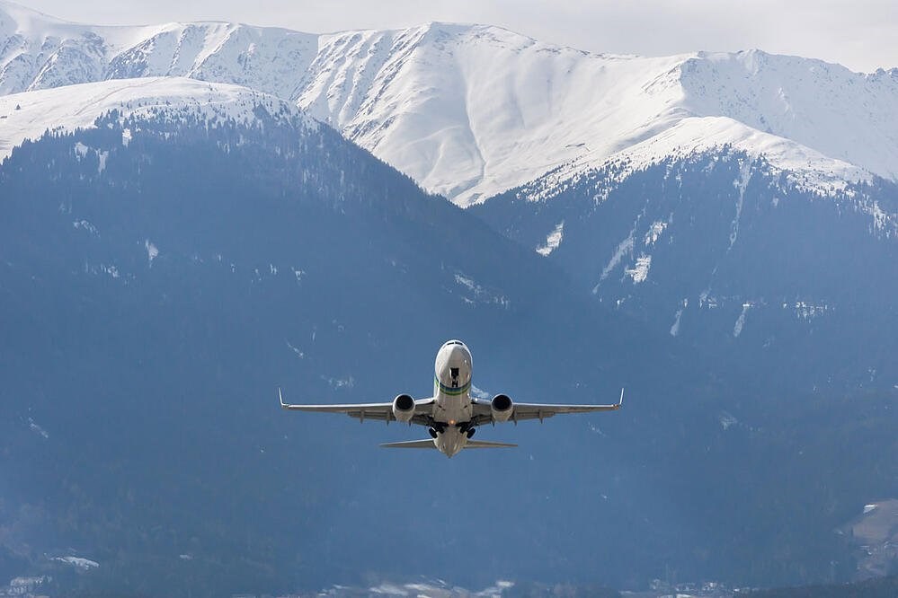 Photo of aircraft in sky with snowy mountains in background