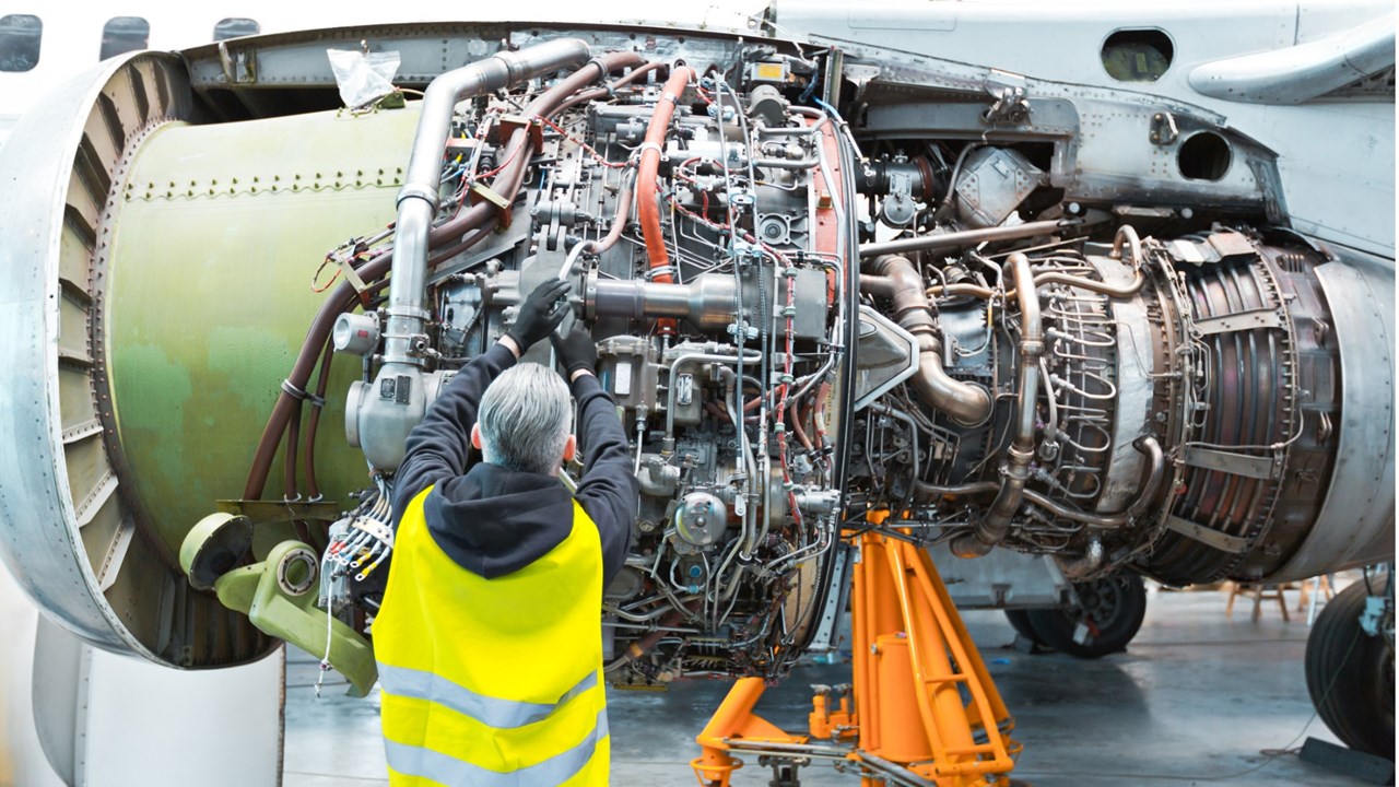 Photo of back view of a mechanic fixing aircraft engine