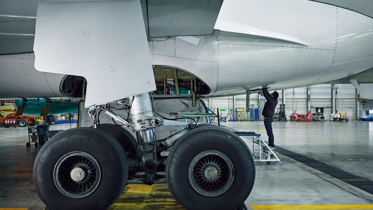 A mechanic works on the underside of an aircraft