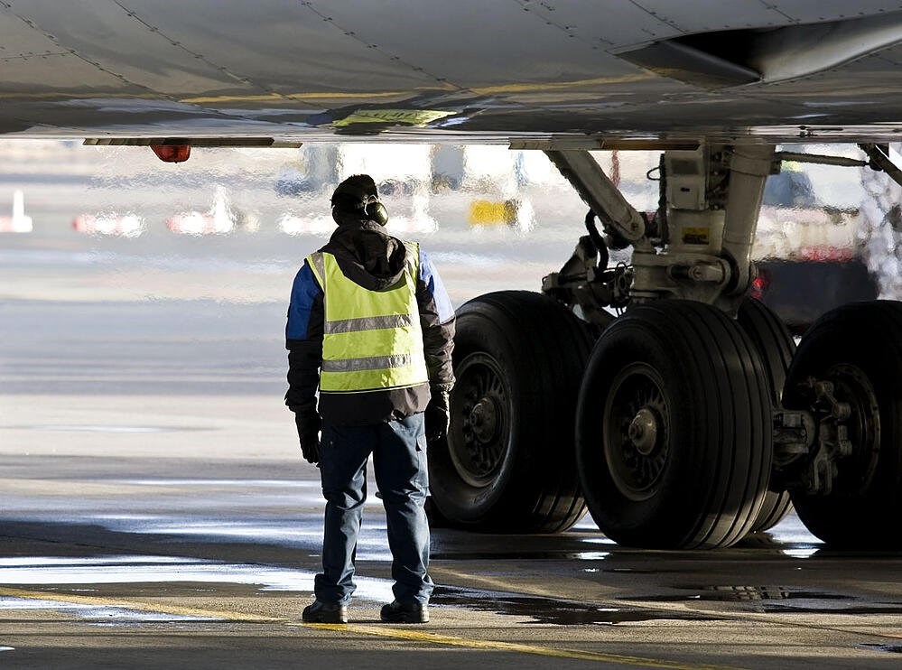 Photo of aircraft maintenance engineer on tarmac under aircraft
